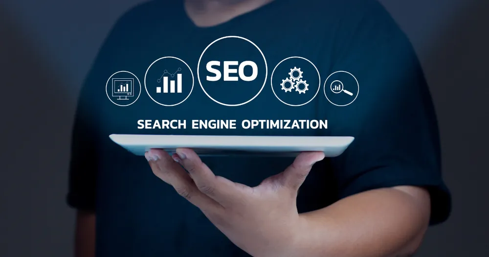 Hand holding a tablet with glowing SEO and search engine optimisation icons above it